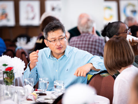 A man and woman conversing at a dining event.