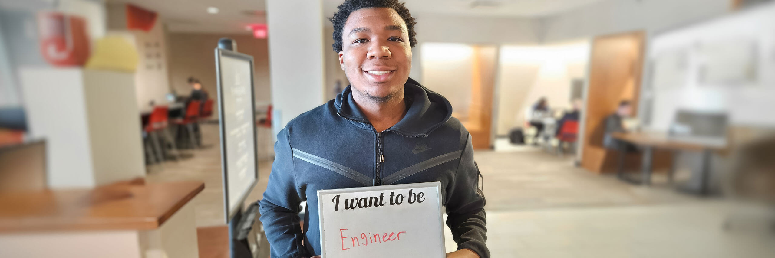 male student holding sign I want to be an engineer