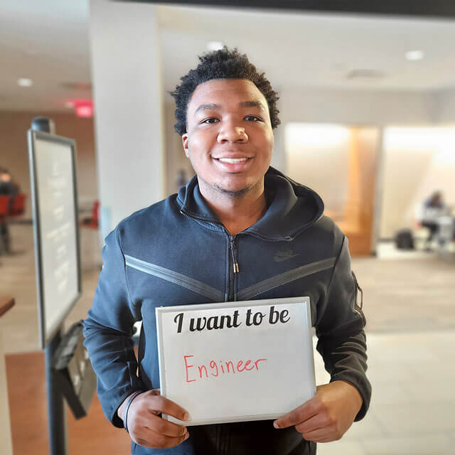 male student holding sign I want to be an engineer