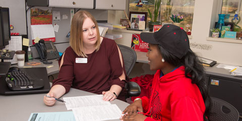 A woman tutoring a student referencing a document on the desk.